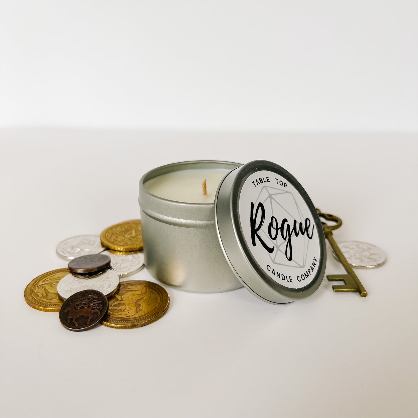 Our four ounce candle. In our Rogue scent it is surrounded by coins and a key.  